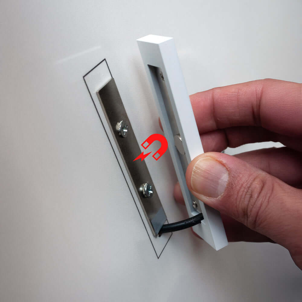 Person installing a white light fixture with a metal base on a wall.